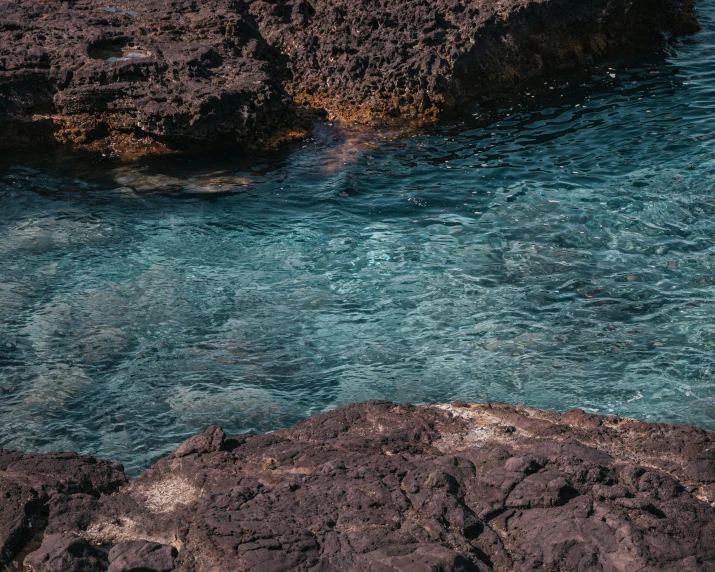 a man standing on top of a rock next to a body of water, an album cover, inspired by Elsa Bleda, pexels contest winner, delicate coral sea bottom, greek pool, australian beach, youtube thumbnail