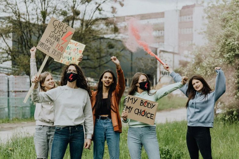 a group of women standing next to each other holding signs, trending on pexels, teenager girl, grassy knoll, avatar image, smoke grenades