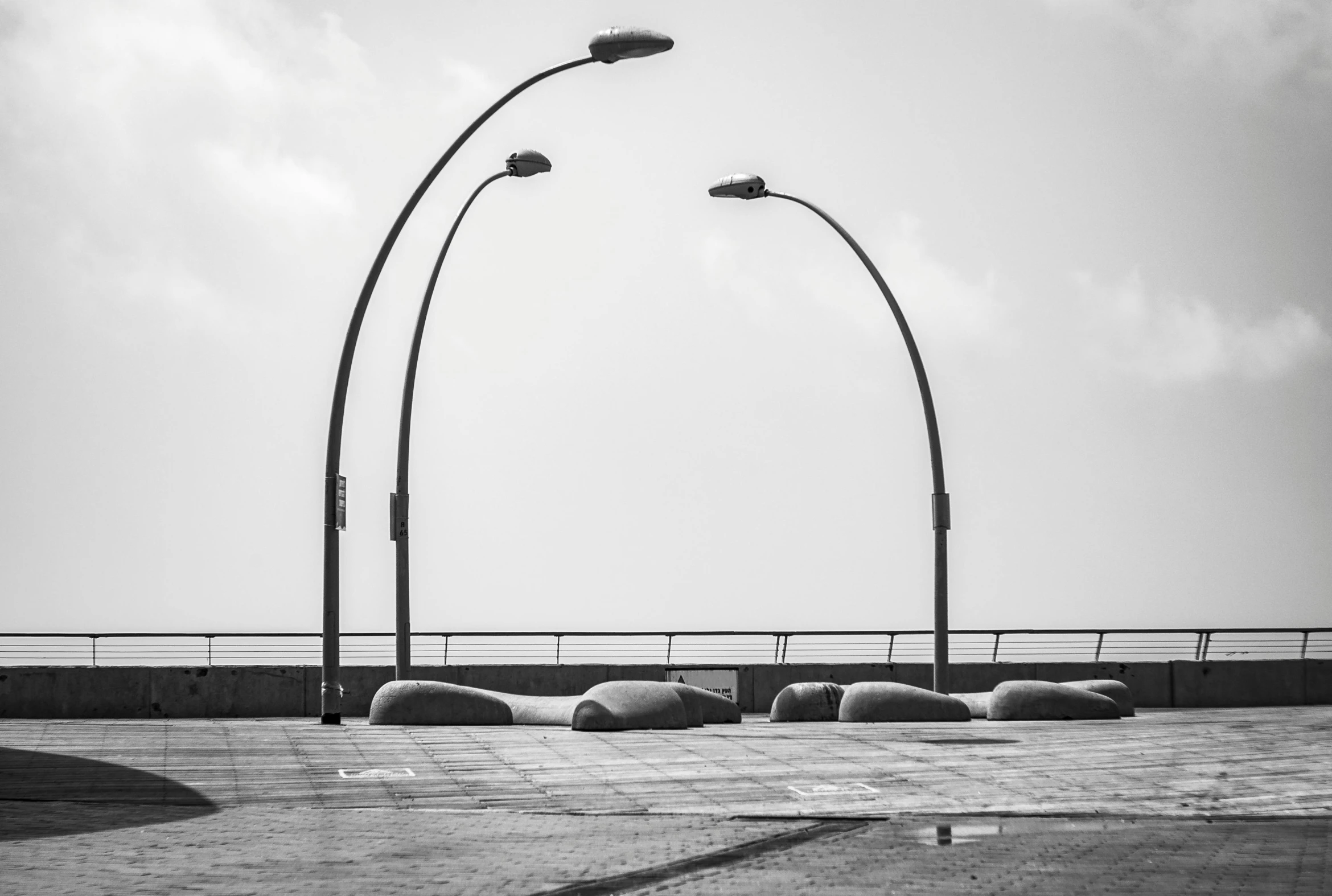a couple of street lights sitting next to each other, a black and white photo, by Etienne Delessert, unsplash, postminimalism, rock arcs, seaside, lamps on ground, tel aviv street