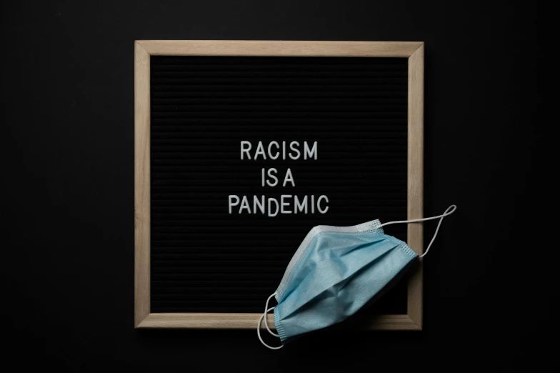 a sign that says racism is a pandemic, trending on pexels, avatar image, dezeen, fan favorite, picture