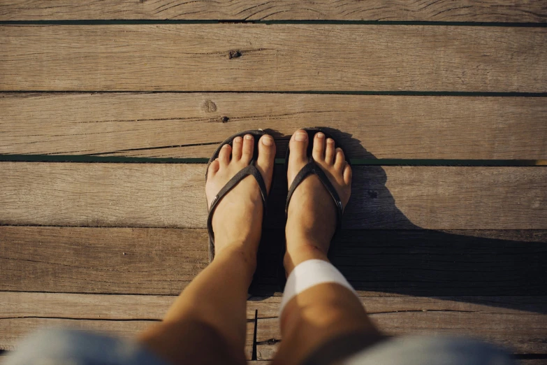 a person standing on a wooden floor wearing flip flops, unsplash, sunburn, wearing a brown, al fresco, very comfy]