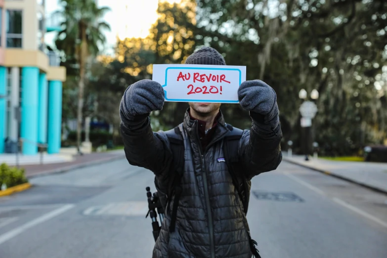 a man holding up a sign in the middle of the street, by Andrew Stevovich, unsplash, florida man, 1 as january, avatar image, ap news photograph