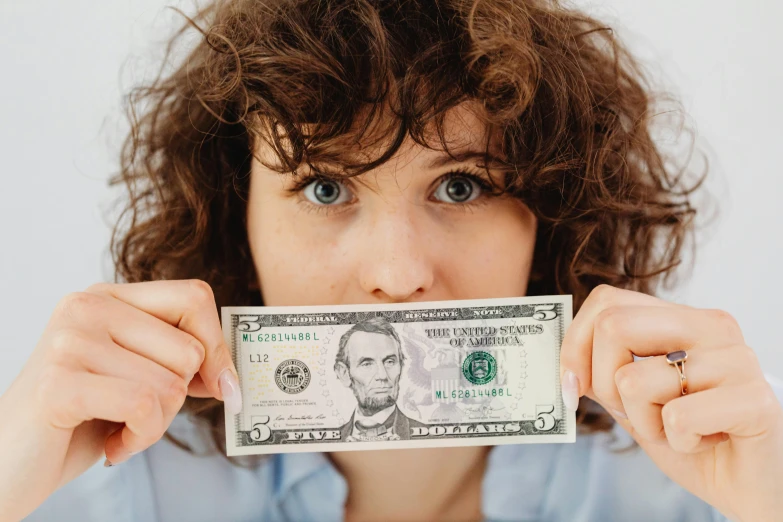 a woman holding a dollar bill in front of her face, pexels contest winner, renaissance, napoleon dynamite, avatar image, girl with brown hair, professional image