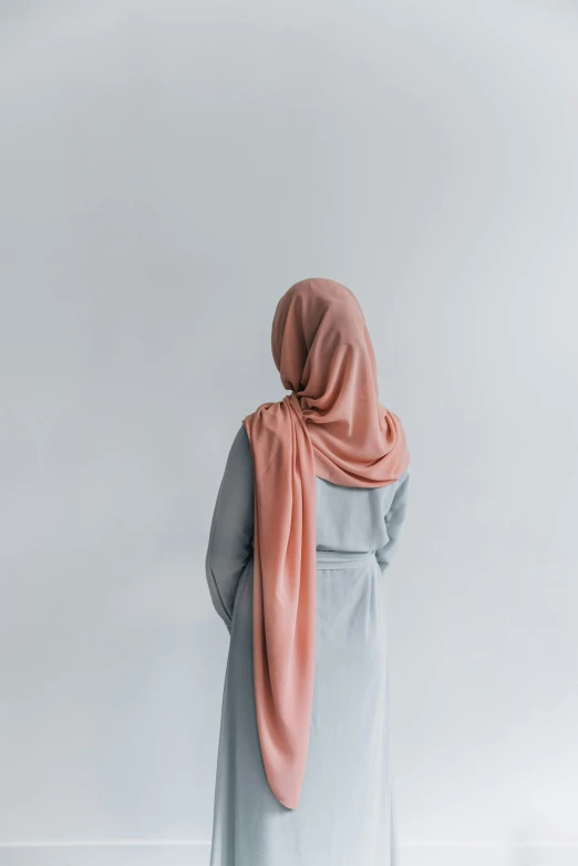a woman wearing a hijab standing in front of a white wall, muted colors. ue 5, coral, made of fabric, photographed for reuters