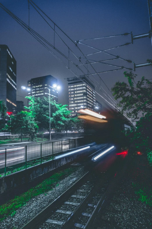 a train traveling through a city at night, by Sengai, unsplash contest winner, overgrown city, grey, green lighting, full frame image