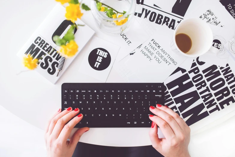 a close up of a person typing on a keyboard, a photo, by Julia Pishtar, trending on pexels, flatlay, typographic, with a bunch of stuff, on a white table