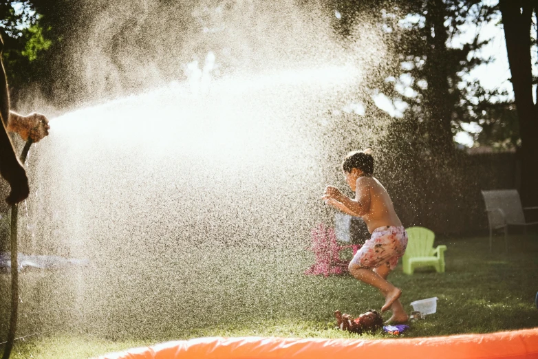a couple of kids playing with a sprinkler, a stipple, by Lee Loughridge, pexels contest winner, sunfaded, cardboard, lachlan bailey, slip n slide