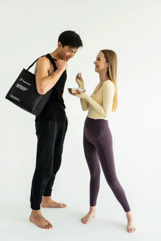 a man and a woman standing next to each other, trending on pexels, renaissance, black leggings, holding mesh bag with bagels, excited, asian male