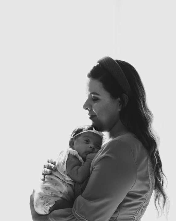 a woman holding a baby in her arms, a black and white photo, by Emma Andijewska, pexels, fine art, alanis guillen, joanna gaines, front facing, good morning