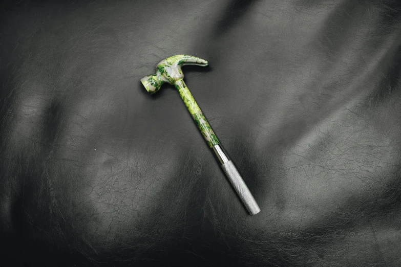 a close up of a hammer on a leather surface, a hyperrealistic painting, inspired by Doc Hammer, unsplash, #green, m c escher, épaule devant pose, mechanic