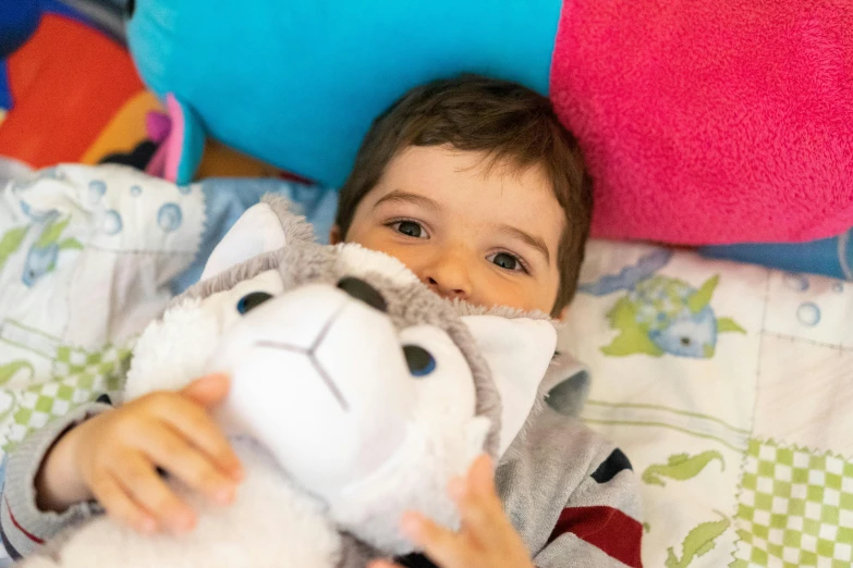 a small child laying in bed with a stuffed animal, a picture, riding a giant silver wolf, close up face detail, multicoloured, liam