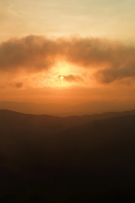 the sun is setting over the mountains in the distance, by Joe Stefanelli, black mountains, orange fog, panoramic, to