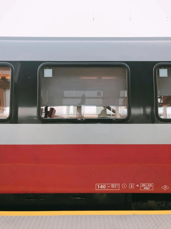 a red and white train stopped at a train station, by Attila Meszlenyi, unsplash, inside of a car, square, 🚿🗝📝, rows of windows lit internally