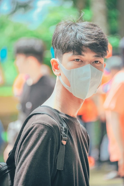 a man wearing a face mask standing in front of a crowd, pexels contest winner, young cute wan asian face, with instagram filters, innocent look, college