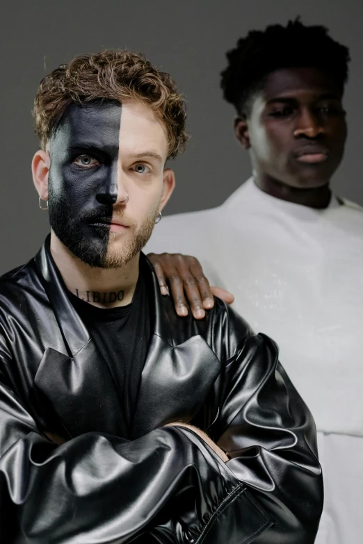 a couple of men standing next to each other, an album cover, inspired by Hendrick van Balen, trending on pexels, white facepaint, pitchblack skin, half and half, post malone