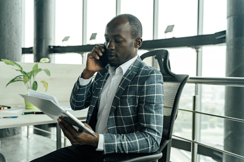 a man sitting in a chair talking on a cell phone, pexels contest winner, hurufiyya, business attire, unmistakably kenyan, trying to read, architect