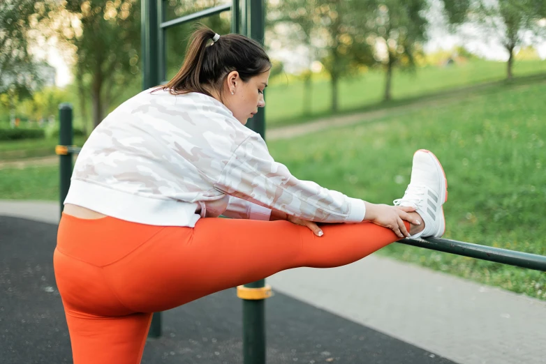 a woman stretching her legs on a pull up bar, trending on pexels, arabesque, white and orange, sitting on a park bench, tights skin, sydney park