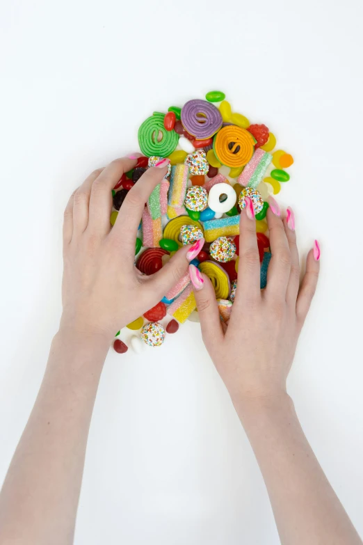 a person holding a bunch of buttons in their hands, an album cover, inspired by Damien Hirst, trending on pexels, 4k polymer clay food photography, long nails, eating, candyland