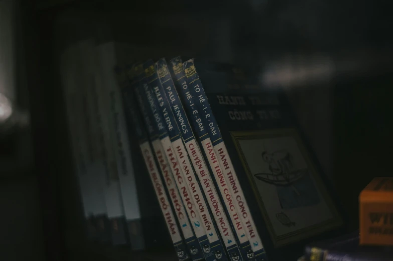 a stack of books sitting on top of a shelf, lain serial experiments, up-close, dimly lit scene, leaked image