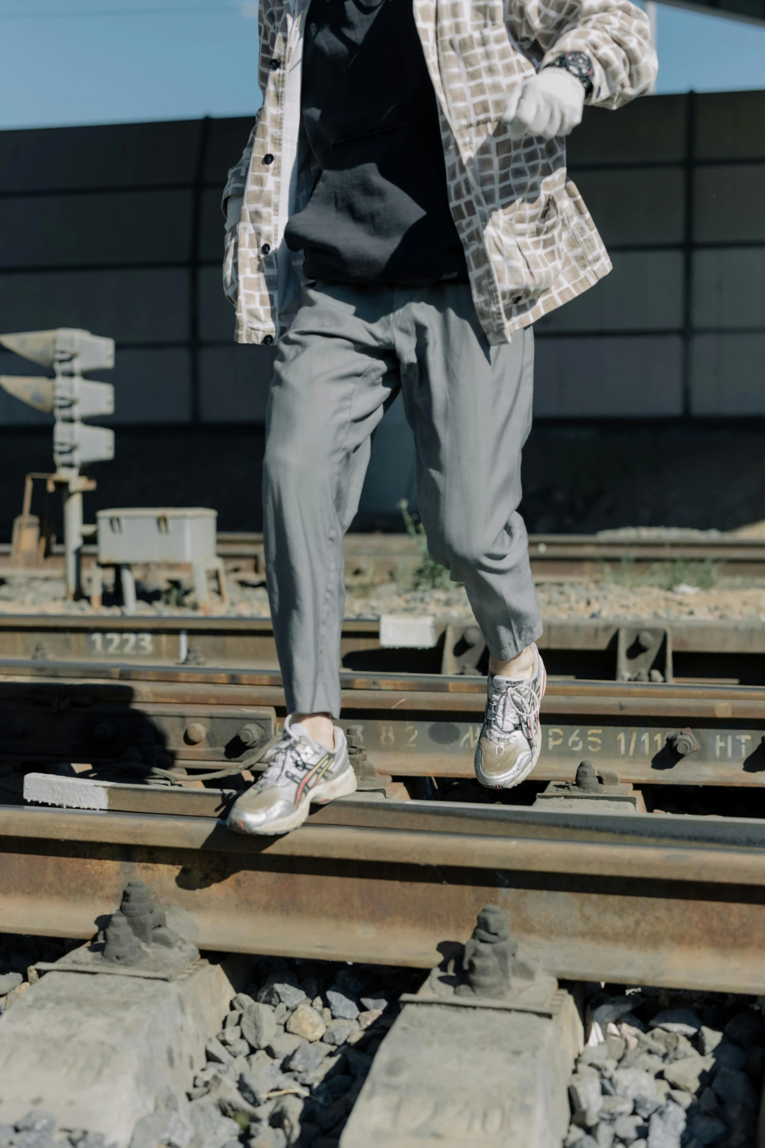 a man that is standing on some train tracks, silver and muted colors, wearing pants, official store photo, platforms