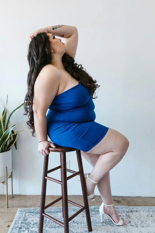 a woman in a blue dress sitting on a stool, by Briana Mora, curvy build, tube-top dress, profile image, skintight dress