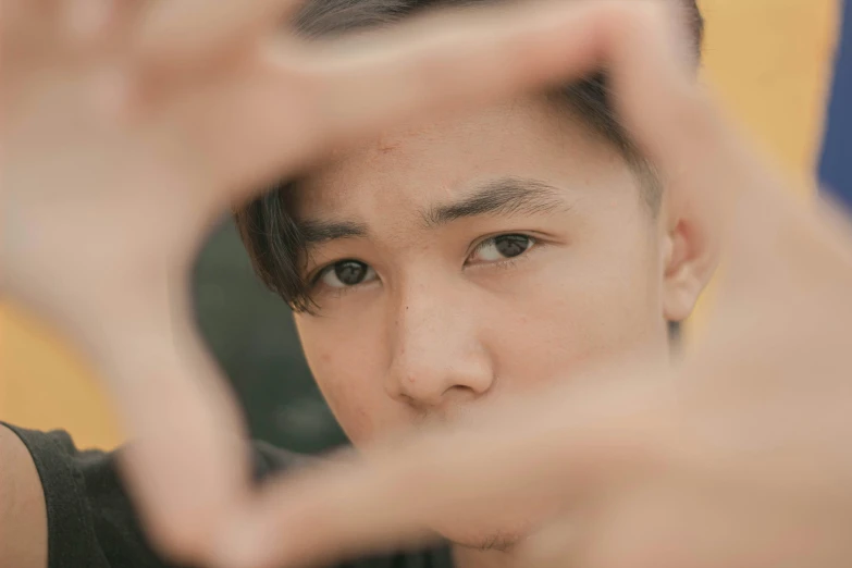 a man making a heart with his hands, inspired by Xia Yong, trending on pexels, realism, young cute wan asian face, looking through a portal, square face, androgynous person