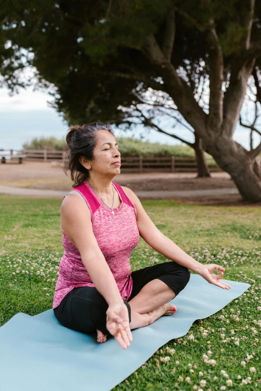 a woman sitting on a yoga mat in a park, bay area, starfish pose, sitting on a lotus flower, full-figure