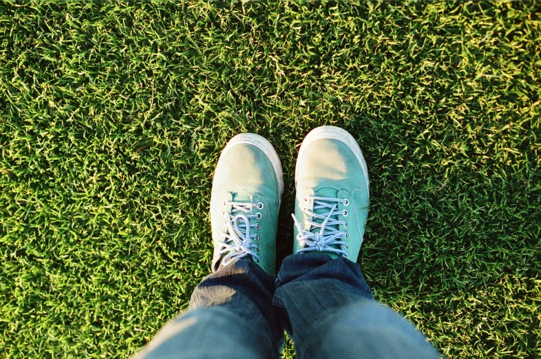 a person standing on top of a lush green field, a picture, acid-green sneakers, with a lush grass lawn, upward perspective, soft blues and greens