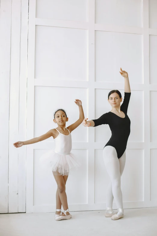 a couple of young girls standing next to each other, arabesque, instruction, in a white room, teaching, foam
