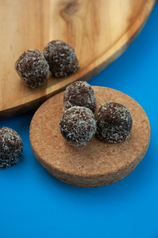 a wooden plate topped with chocolate covered fruit, energy spheres, manuka, medium angle, thumbnail