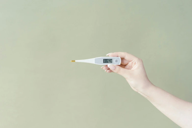 a person holding a digital thermometer in their hand, by Nicolette Macnamara, unsplash, happening, contracept, single long stick, digital render, umami