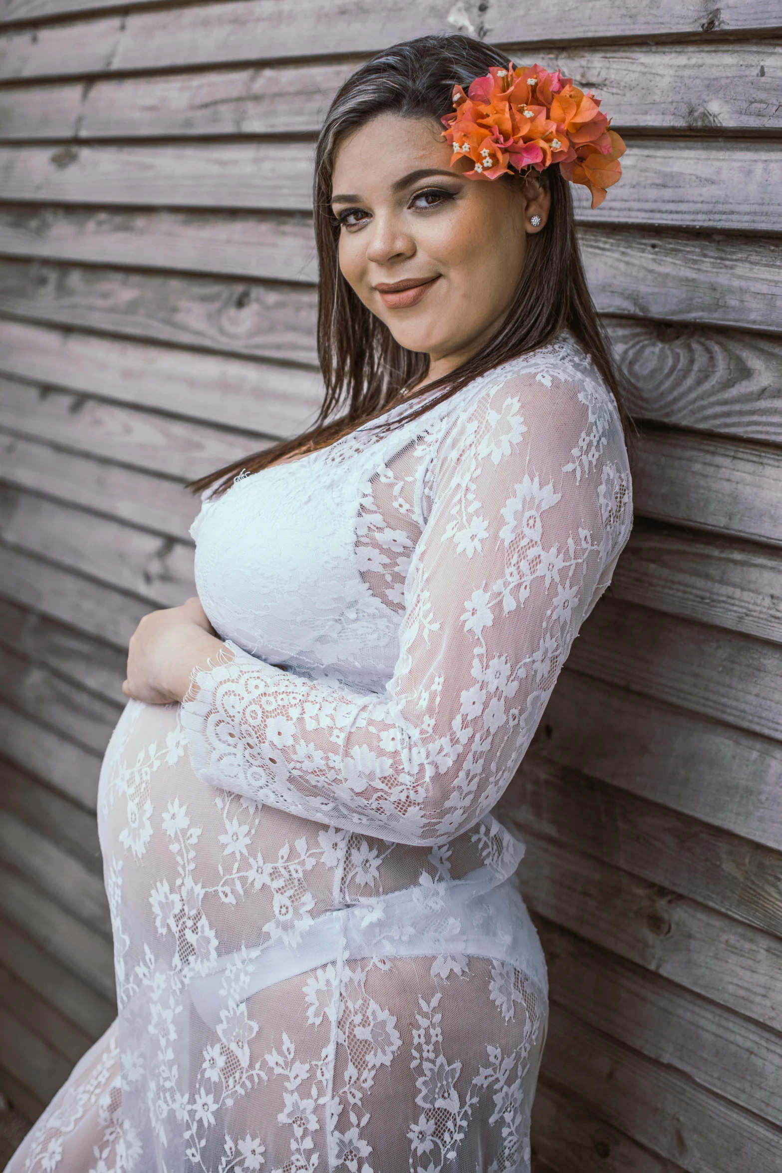 a pregnant woman leaning against a wall with a flower in her hair, white lace clothing, she is smiling, 5 0 0 px models, low quality photo