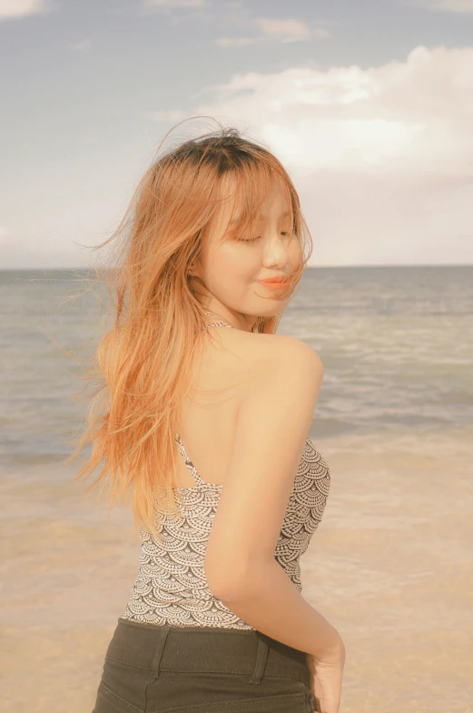 a woman standing on a beach next to the ocean, an album cover, inspired by Kim Jeong-hui, light brown long wavy hair, profile image, sun yunjoo, ( ( ( kauai ) ) )