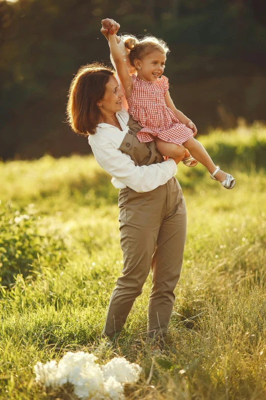 a woman holding a little girl in a field, breeches, feeling good, stability at last, lush surroundings