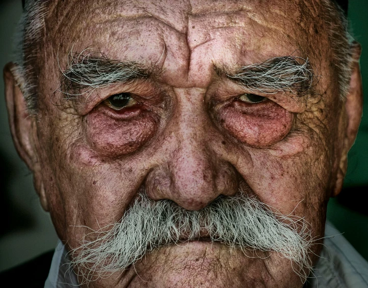 a close up of an old man with a mustache, a colorized photo, by Adam Marczyński, pexels contest winner, weathered olive skin, grumpy [ old ], shot of face, wideangle portrait