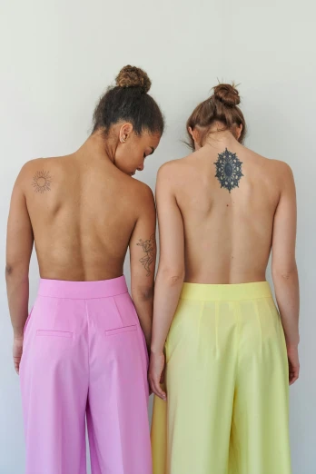 a couple of people standing next to each other, a tattoo, by Nina Hamnett, crop yoga short, nonbinary model, back and standing, different colors