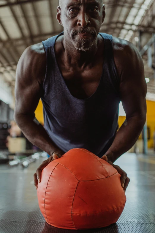 a man holding a medicine ball in a gym, by Joseph Severn, pexels contest winner, man is with black skin, gif, color photo, ripped