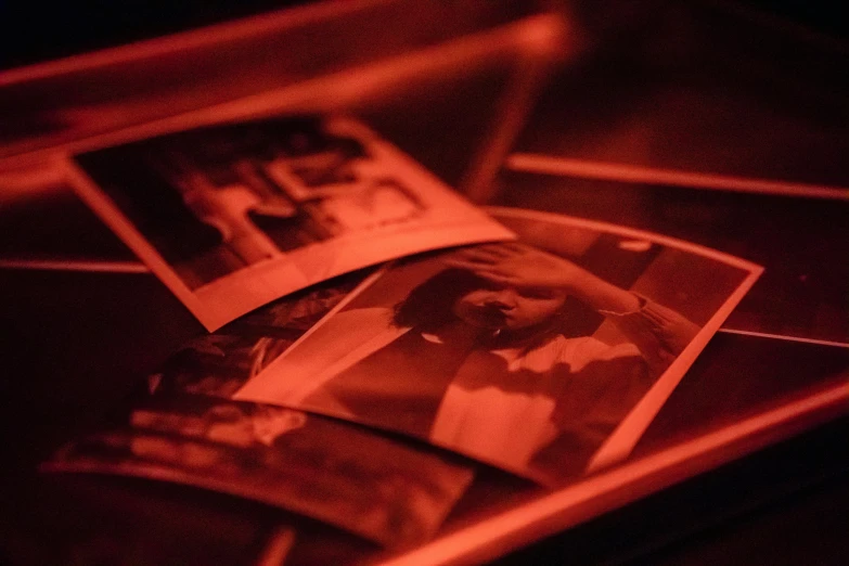 a couple of photos sitting on top of a table, by Daniel Lieske, unsplash, process art, red and orange glow, old photobook, taken in night club, picture frames