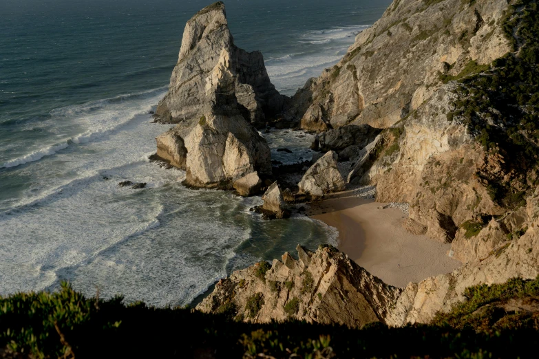 a couple of large rocks sitting on top of a beach, by Jacob Pynas, pexels contest winner, portugal, steep cliffs, slide show, high - angle view