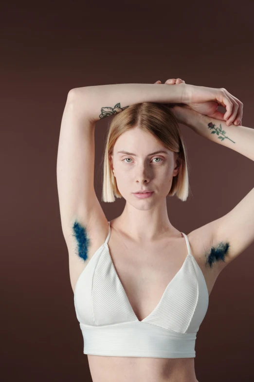 a woman with a tattoo on her arm, inspired by Elsa Bleda, trending on pexels, renaissance, blue paint on top, armpit, plain background, square