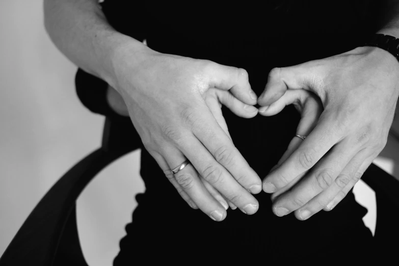 a woman making a heart with her hands, a black and white photo, pregnant, unclipped fingernails, amanda lilleston, gentleman