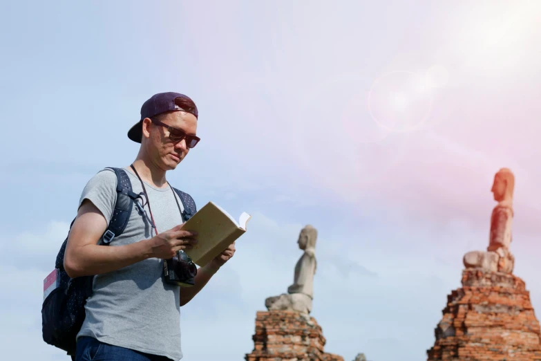 a man reading a book in front of a statue, pexels contest winner, happening, standing before ancient ruins, avatar image, bright sunny day, asian man