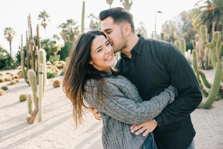 a man and woman standing next to each other in front of cacti, pexels contest winner, happening, kissing smile, avatar image, hispanic, cuddling