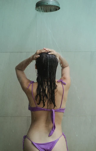 a woman in a purple bikini standing in a shower, pexels, back of the hair, gif, bedhead, college