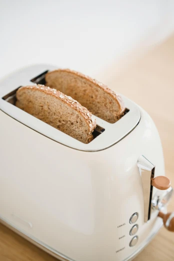 a toaster with two slices of bread in it, by Everett Warner, unsplash, minimalism, white mechanical details, light tan, delightful surroundings, back towards camera