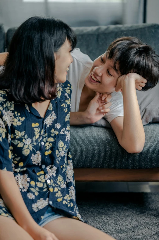 a woman sitting on top of a couch next to a man, inspired by Ruth Jên, trending on pexels, incoherents, earing a shirt laughing, lesbian embrace, young asian girl, patterned