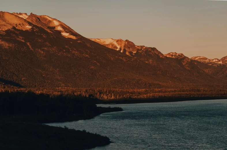 a large body of water with mountains in the background, by Andrei Kolkoutine, unsplash contest winner, hurufiyya, late afternoon light, brown, carson ellis, instagram post