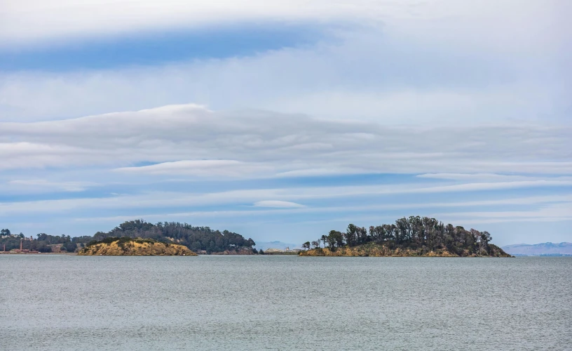 a large body of water with a small island in the background, inspired by Wilhelm Marstrand, unsplash, hurufiyya, chile, clouded sky, slide show, delightful surroundings