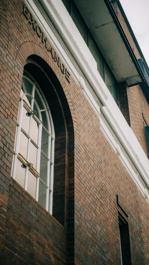 a clock mounted to the side of a brick building, by Lee Loughridge, unsplash, art nouveau, low quality photo, window ( city ), 1980s photograph, arched doorway