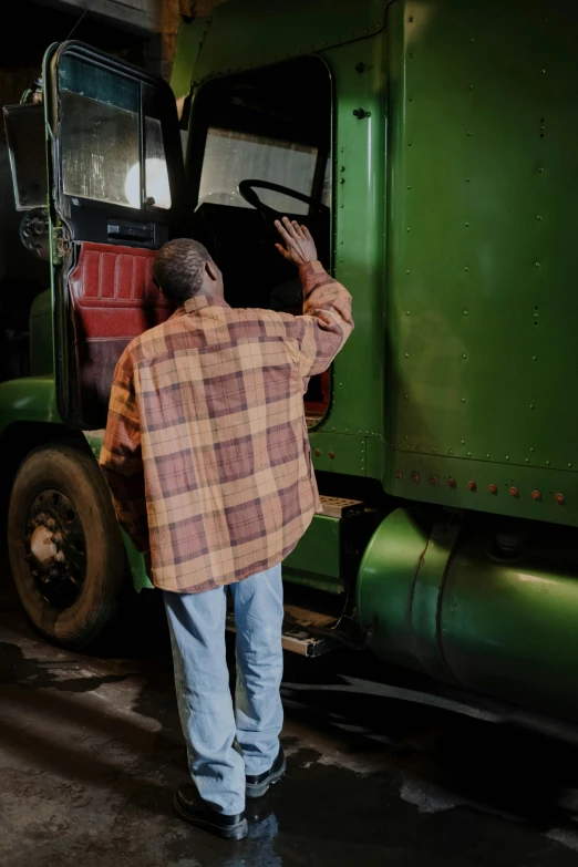 a man standing in front of a green truck, by Dan Frazier, photo of poor condition, facing away, flannel, photograph credit: ap